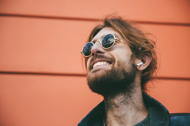 Feche o retrato de um homem barbudo feliz em fones de ouvido