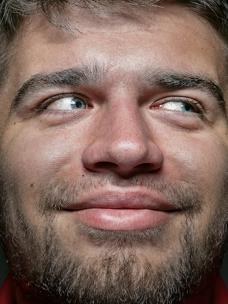 Feche o retrato de um homem caucasiano jovem e emocional. modelo masculino com pele bem cuidada e expressão facial brilhante. conceito de emoções humanas. sorrindo e parece feliz.