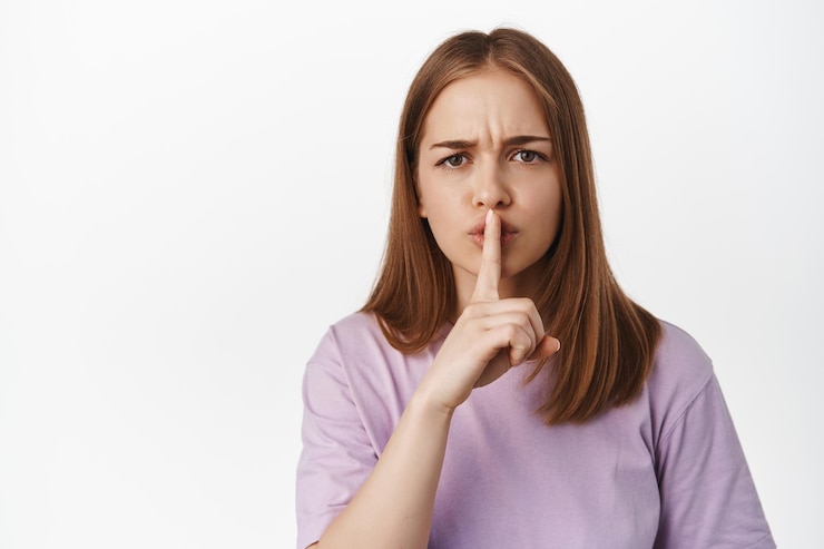Foto grátis feche o retrato de uma garota zangada calando, franzindo a testa chateada e calando, gesto shhh, diga para ficar quieto, repreendendo a pessoa barulhenta, de pé contra um fundo branco