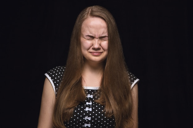 Foto grátis feche o retrato de uma jovem isolada no fundo preto do estúdio. photoshot de emoções reais de modelo feminino. chorando de olhos fechados, triste e sem esperança. expressão facial, conceito de emoções humanas.