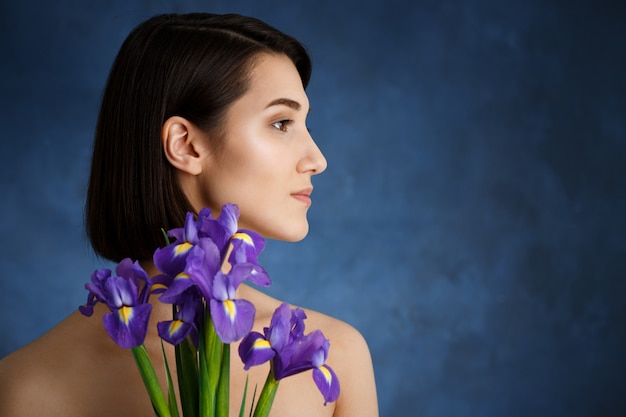 Feche o retrato de uma jovem mulher concurso com flores violetas sobre parede azul