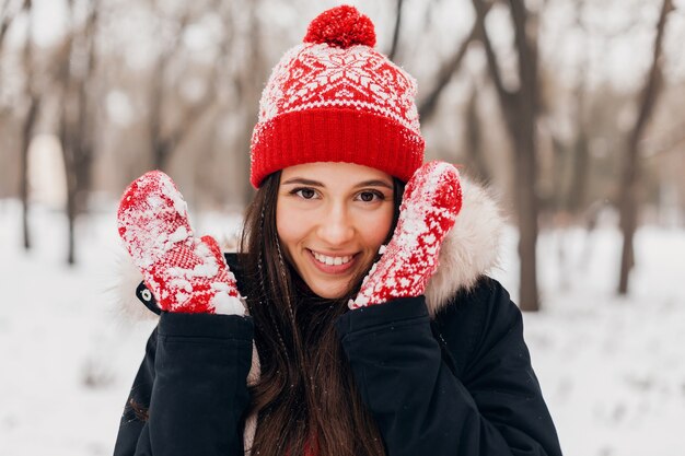 Feche o retrato de uma jovem mulher feliz, sorridente, muito sincera, com luvas vermelhas e chapéu de malha, vestindo um casaco de pele, andando brincando no parque na neve, roupas quentes, se divertindo