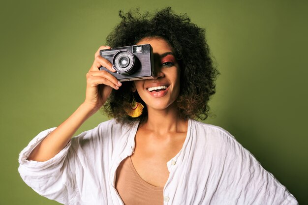 Feche o retrato de uma mulher Afican segurando a câmera fotográfica retrô e rindo.