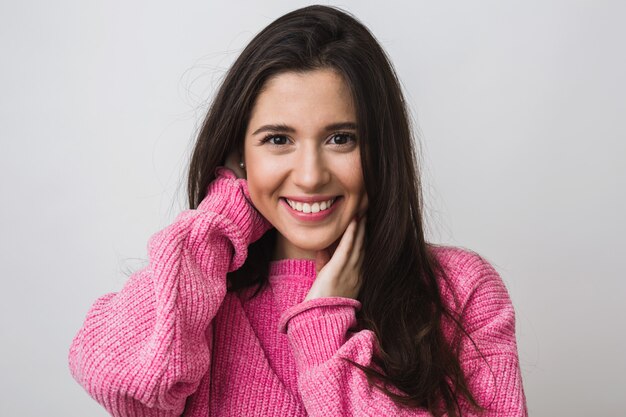 Feche o retrato de uma mulher atraente feliz em um suéter rosa quente, cabelo comprido, aparência natural, sorriso sincero, humor positivo, isolado