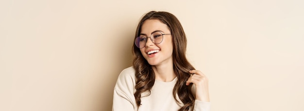 Feche o retrato de uma mulher morena estilosa de óculos rindo e sorrindo posando de óculos contra