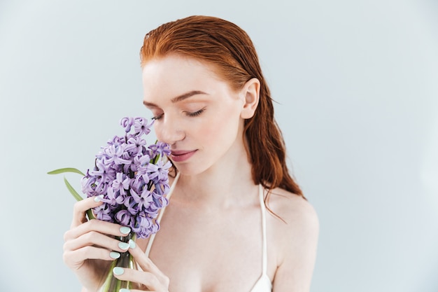 Feche o retrato de uma mulher ruiva cheirando flores jacintos