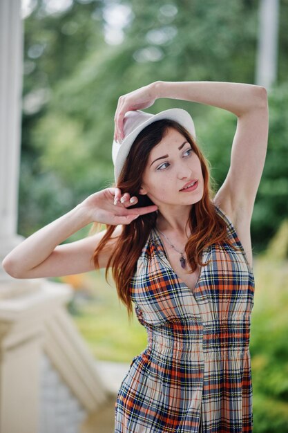 Feche o retrato do desgaste da menina no chapéu posando perto de colunas de construção vintage