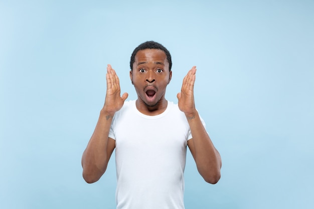 Feche o retrato do jovem modelo masculino afro-americano na camisa branca. emoções humanas, expressão facial, anúncio ou conceito de apostas. chocado, animado, espantado.