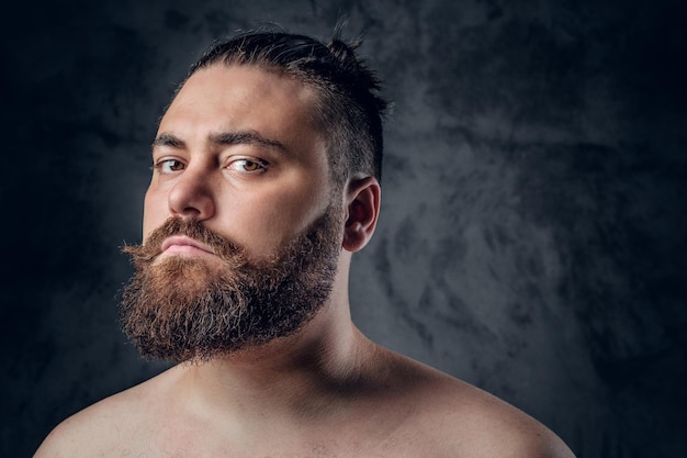 Feche o retrato do macho de barba sem camisa em fundo cinza.