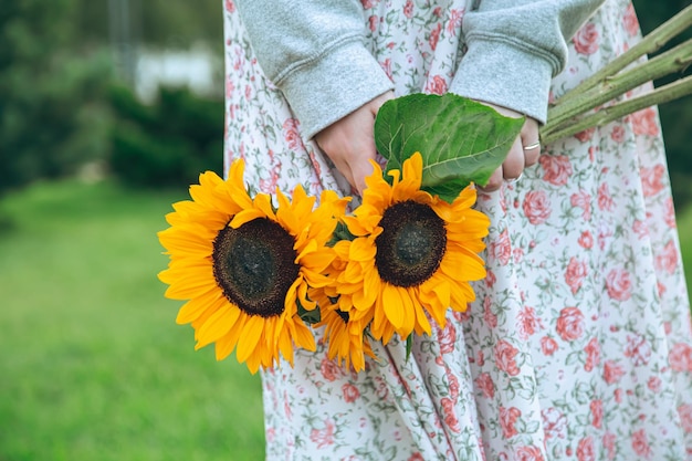 Feche um buquê de girassóis em mãos femininas em um fundo desfocado