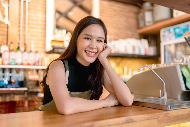 Felicidade alegre mulher asiática em uniforme café de pequenas empresas ásia mulher proprietária trabalhando em coffeeshop barista feminina chinesa fazendo café com máquina de café na loja de café