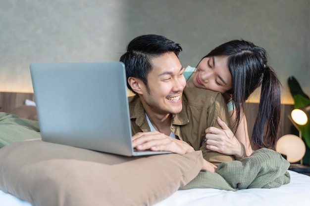 Felicidade casal asiático trabalhando em casa com alegria e felicidade abraçando junto com amor e alegre casal de casados trabalhando com tablet no quarto em casa com abraço apoio marido