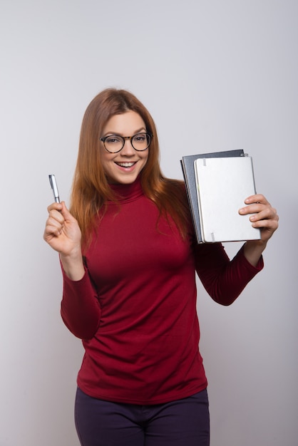 Foto grátis feliz aluna com livros didáticos e caneta