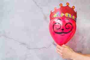 Foto grátis feliz aniversário coroa no balão rosa contra parede rachada