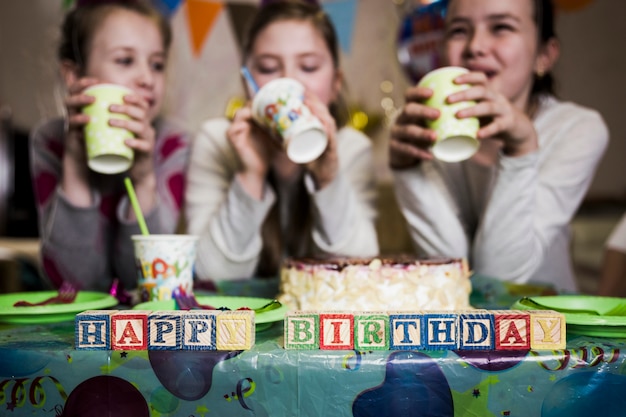 Foto grátis feliz aniversário escrevendo perto de garotas bebendo