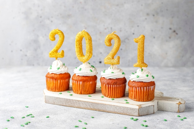 Feliz ano novo de 2021, cupcakes com velas douradas.