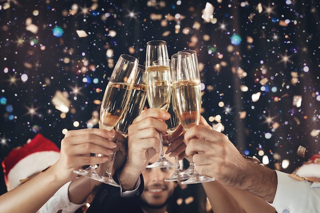 Feliz ano novo. tinindo taças de champanhe nas mãos sobre fundo de luzes brilhantes