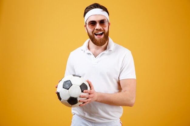 Feliz barbudo esportista segurando bola de futebol
