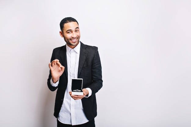 Foto grátis feliz cara bonito com camisa branca de luxo, jaqueta preta segurando o presente e sorrindo. tempo de férias, fazendo surpresa, ornamentação, bom humor.