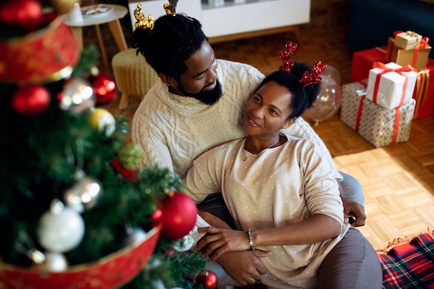 Feliz casal afro-americano relaxando na árvore de Natal em casa