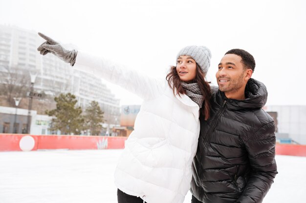 Feliz casal apaixonado patinando na pista de gelo ao ar livre.