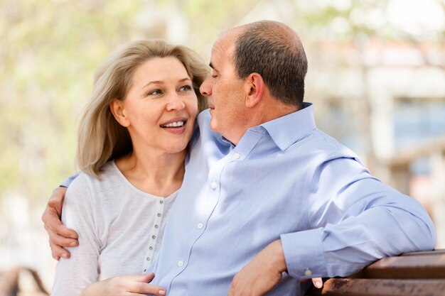 Feliz casal de idosos abraçando um banco