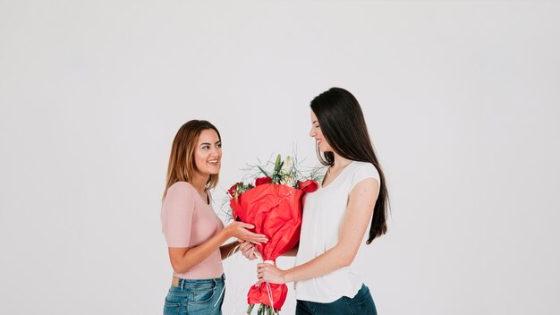 Feliz casal de lésbicas com buquê de flores