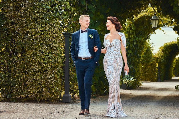 Foto grátis feliz casal de noivos está andando pelo jardim incrível.