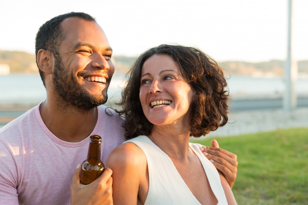 Feliz casal descontraído, bebendo cerveja e conversando ao ar livre