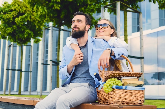 Feliz casal moderno em um encontro faz um piquenique em uma cidade.