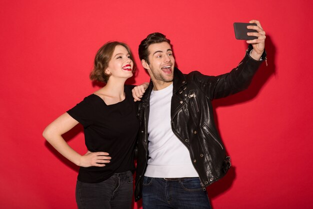 Foto grátis feliz casal punk posando e fazendo selfie em smartphone