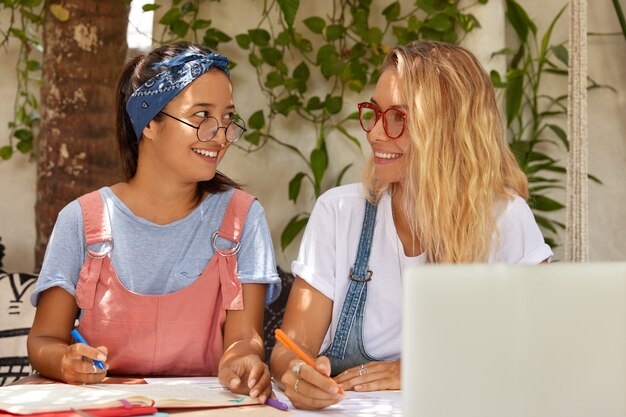 Feliz e satisfeito e sorridente estudante universitário adolescente segurando canetas, prepare-se para escrever o trabalho do curso