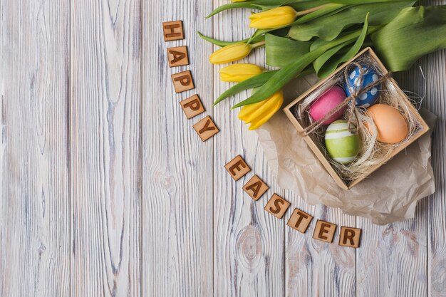 Feliz Easter escrevendo perto de tulipas e ovos