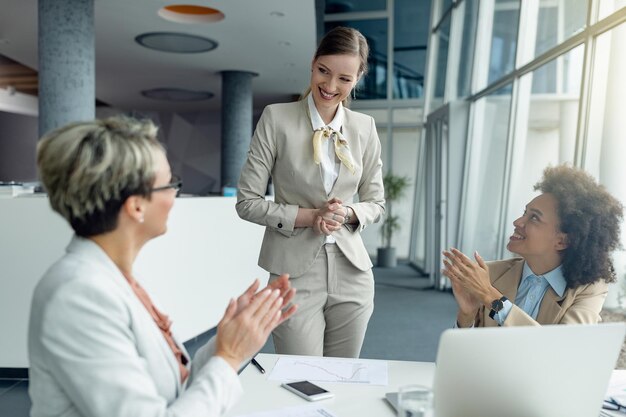 Feliz empresária recebendo aplausos após apresentação bem-sucedida em uma reunião