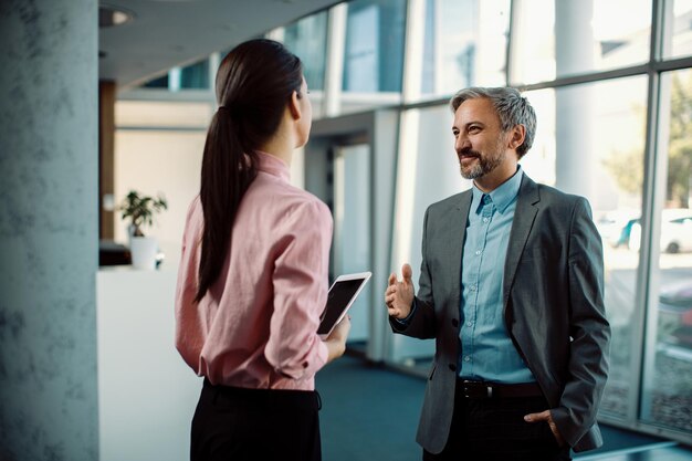 Feliz empresário falando com sua colega em um corredor