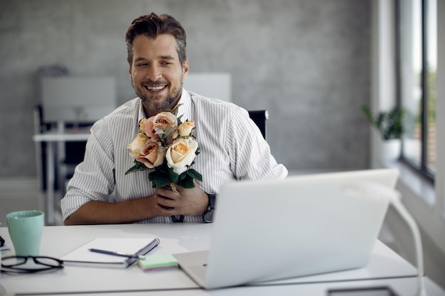 Feliz empresário falando enquanto tem um encontro online sobre laptop no escritório