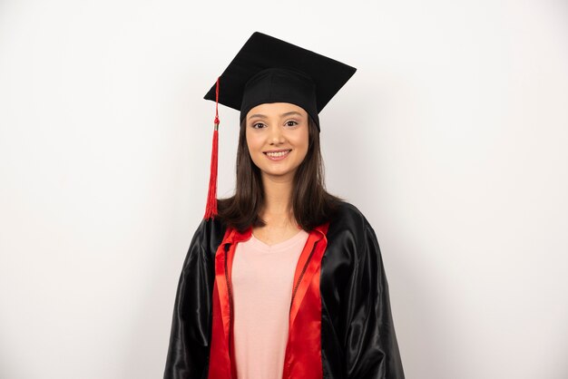 Feliz estudante de pós-graduação em vestido de pé sobre fundo branco.