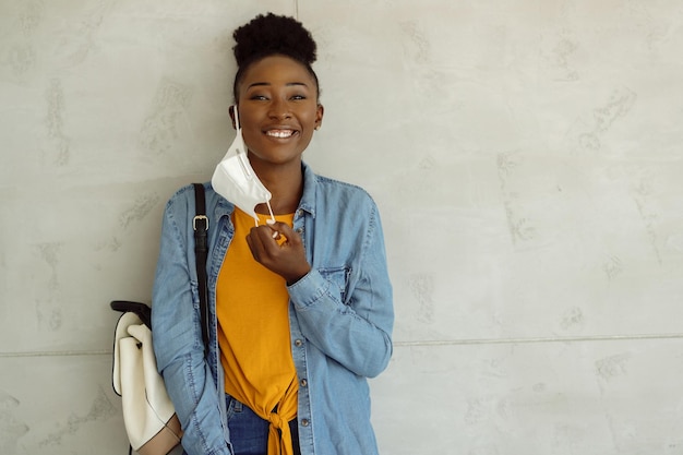 Feliz estudante universitário afro-americano tirando sua máscara protetora