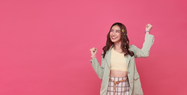 Foto grátis feliz extasiada alegre mulher asiática punho para cima levantar gesto de vitória isolado em rosa cópia de fundo de espaço