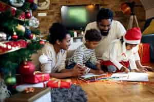 Foto grátis feliz família afro-americana desenhando no dia de natal em casa