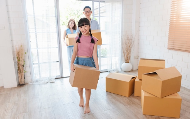 Feliz família asiática segurando uma caixa de papelão corre para a nova casa. conceito de realocação