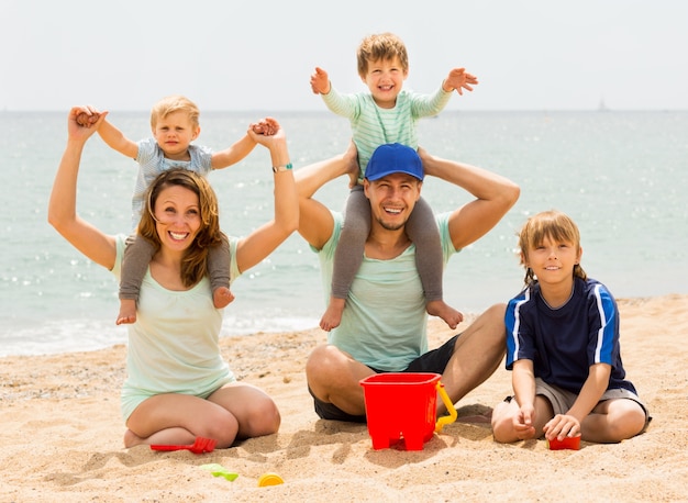 Feliz família de cinco sorrindo na praia do mar