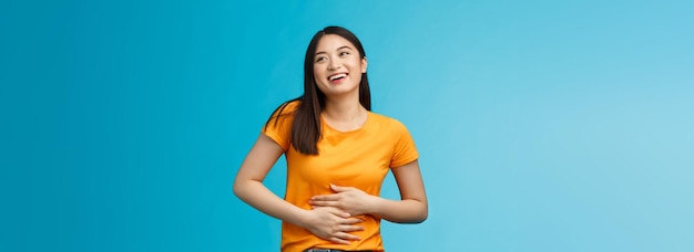 Foto grátis feliz garota asiática bonita sente satisfação depois de comer comida favorita sorrindo amplamente rubbi