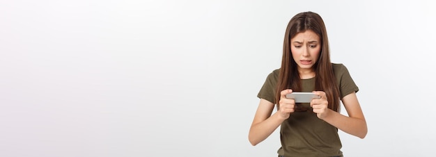 Foto grátis feliz garota morena atraente comemorando a vitória no videogame no smartphone isolado sobre fundo cinza