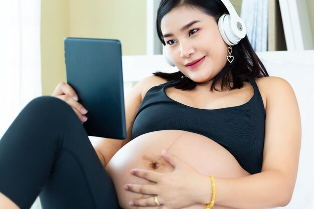 Feliz grávida ouvindo música do tablet