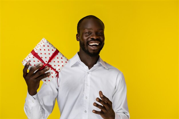 Feliz homem Africano sorrindo para a câmera e segurando um presente