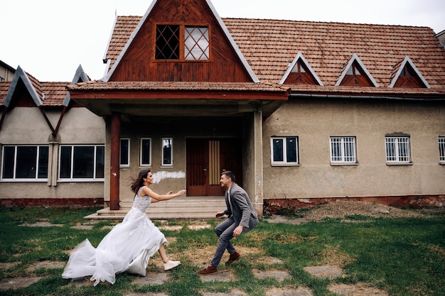 Foto grátis feliz homem e mulher vestida com roupas oficiais na frente do antigo prédio aconchegante correndo