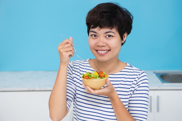 Feliz jovem asiática com salada de legumes