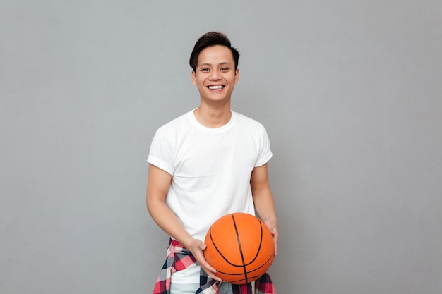 Foto grátis feliz jovem asiático com bola de basquete