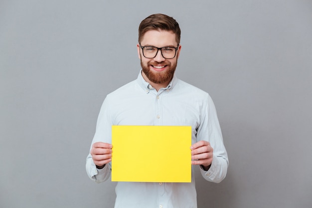 Feliz jovem barbudo empresário segurando papel em branco